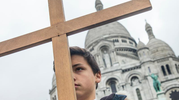 A boy stands with cross outside Sacre Coeur basilica in Paris April 3. Catholic churches in France have been placed under police protection and urged to take extra security measures against possible Islamist attacks before the Aug. 15 feast of the Assumption. (CNS photo/Etienne Laurent, EPA) See FRANCE-CHURCHES-ALERT Aug. 13, 2015.